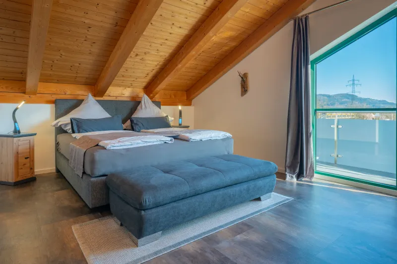 Schlafzimmer 1 mit Boxspringbett, Holzdecke und Tür zum Sonnenbalkon