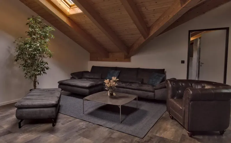 Wohnbereich mit Ledercouch, Chesterfield-Sessel und Dachfenster